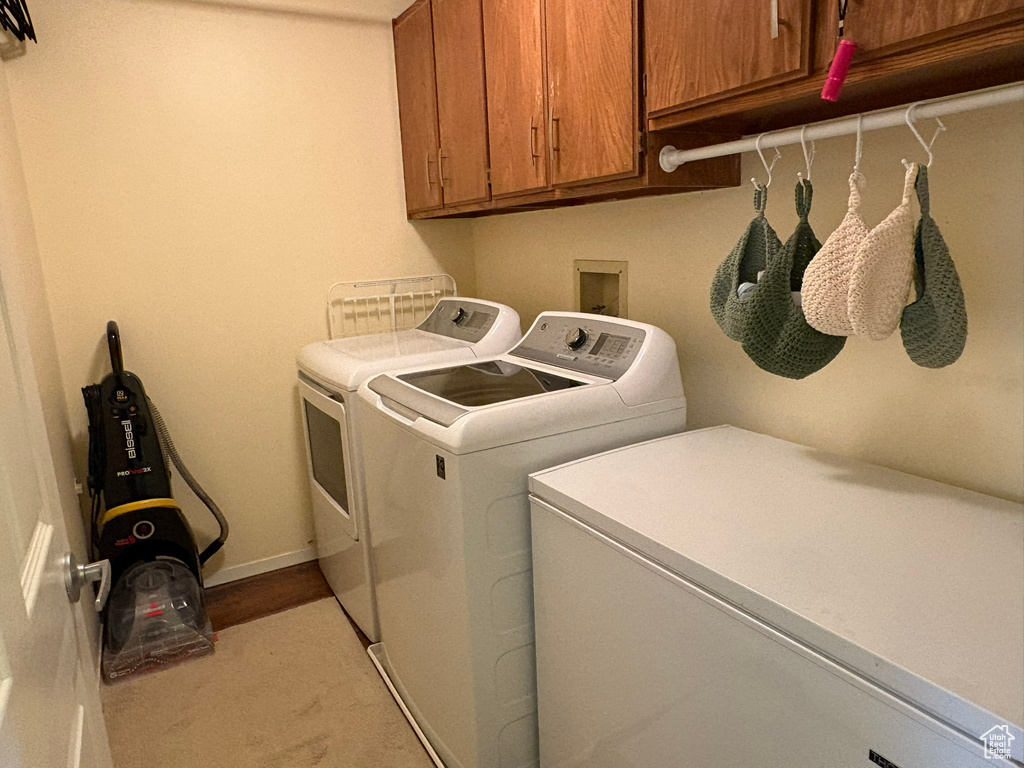 Laundry room with washer and dryer, cabinet space, and light carpet