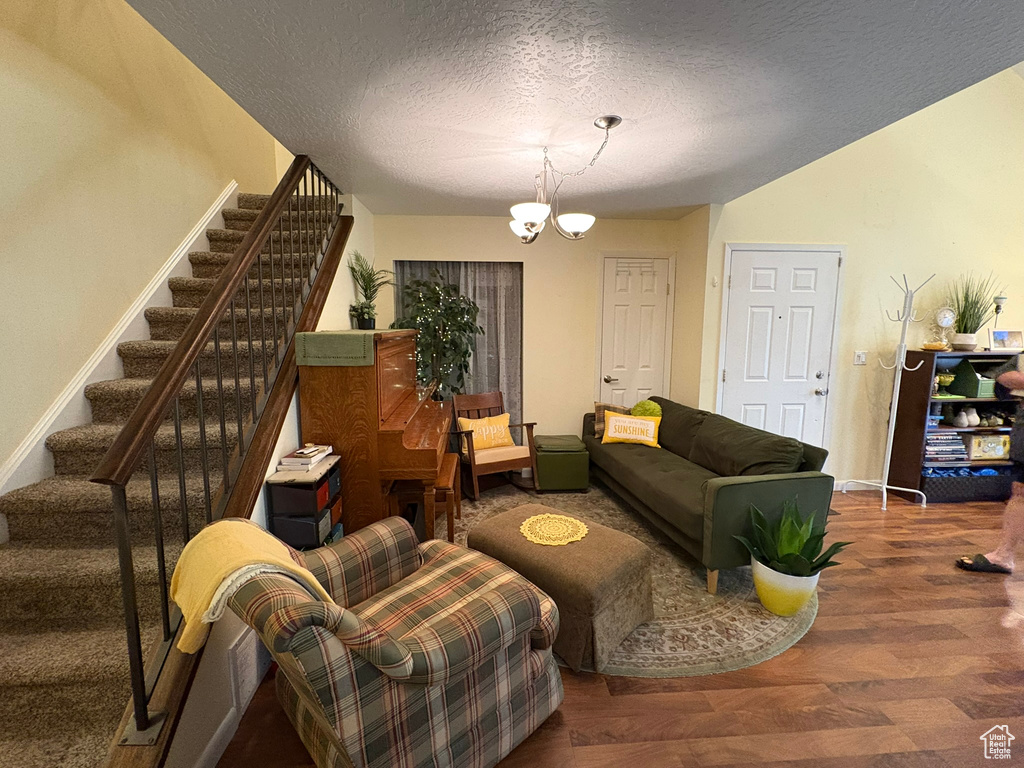 Living area featuring stairway, a textured ceiling, wood finished floors, and a chandelier