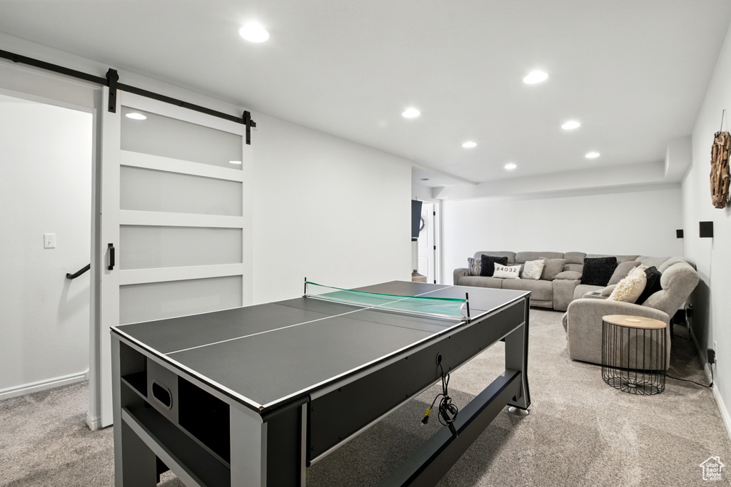 Recreation room with a barn door, light carpet, and recessed lighting