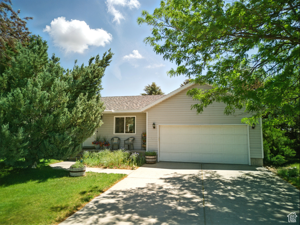 View of front of home with driveway, a garage, a shingled roof, and a front lawn