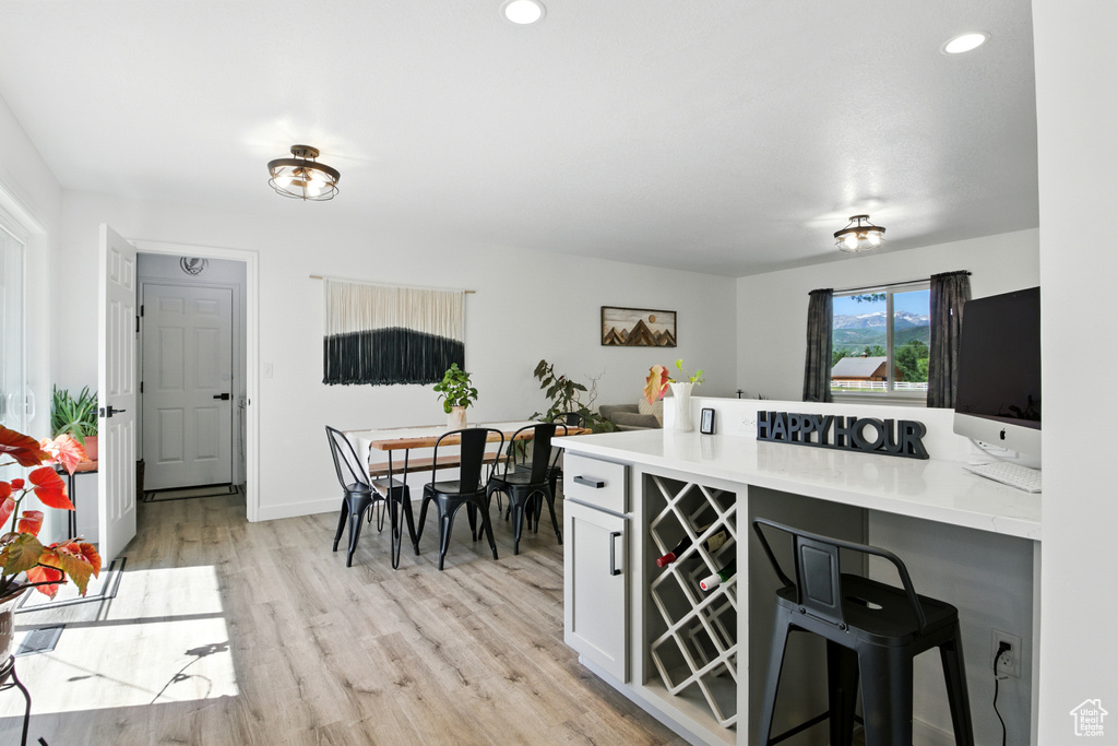 Kitchen with a kitchen breakfast bar, a peninsula, light wood finished floors, light countertops, and recessed lighting