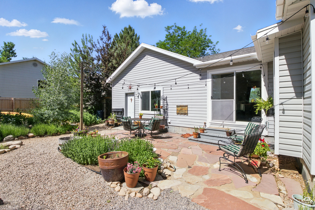 Back of property featuring a patio area, entry steps, and a shingled roof