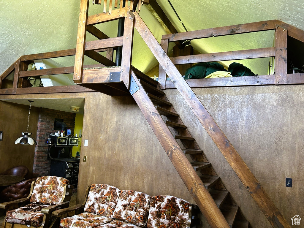 Staircase featuring a textured wall and vaulted ceiling