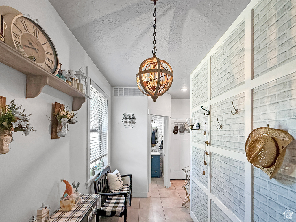 Corridor featuring a chandelier, light tile patterned floors, and a textured ceiling