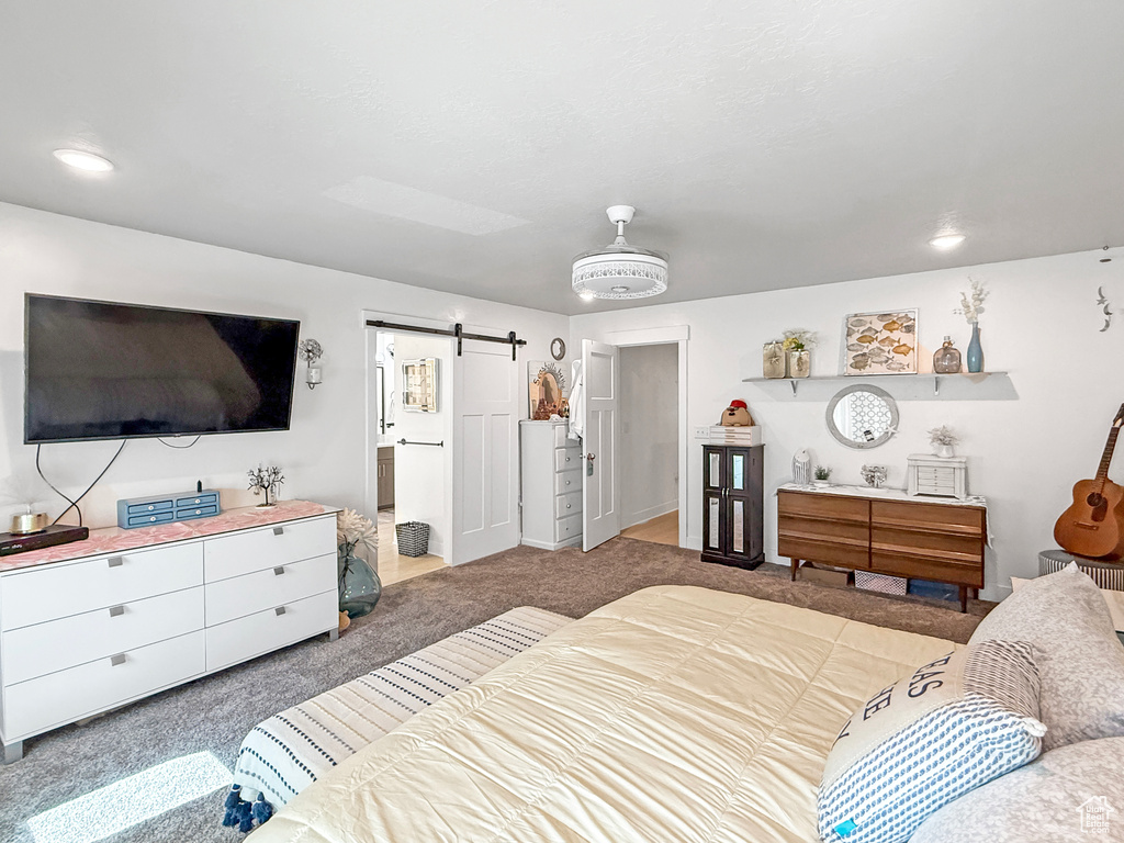 Carpeted bedroom with a barn door and ensuite bathroom