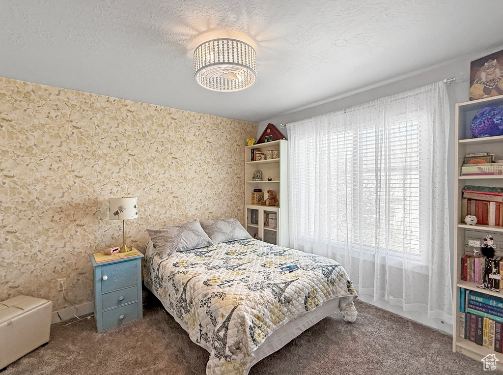 Bedroom featuring carpet, a chandelier, and wallpapered walls