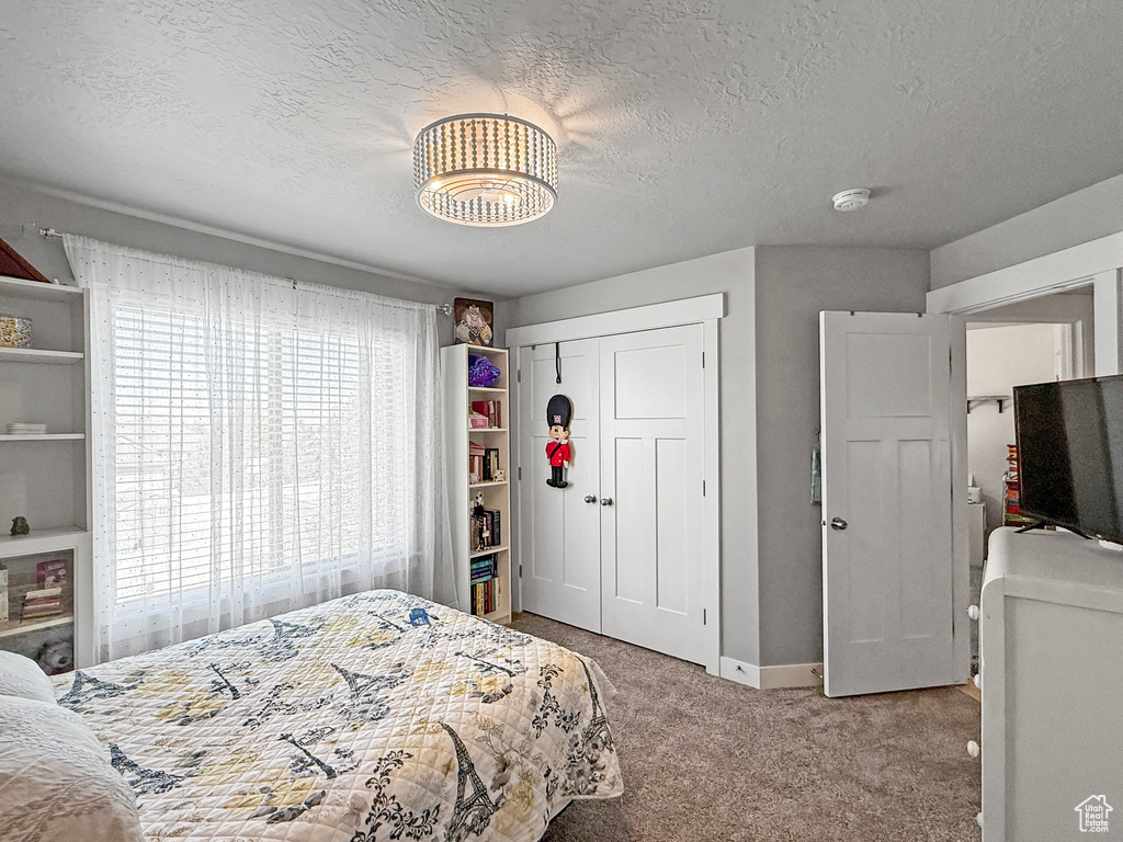 Bedroom with carpet floors, a textured ceiling, and a closet