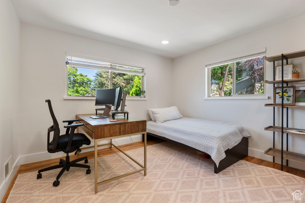 Bedroom with multiple windows, wood finished floors, an office area, and recessed lighting