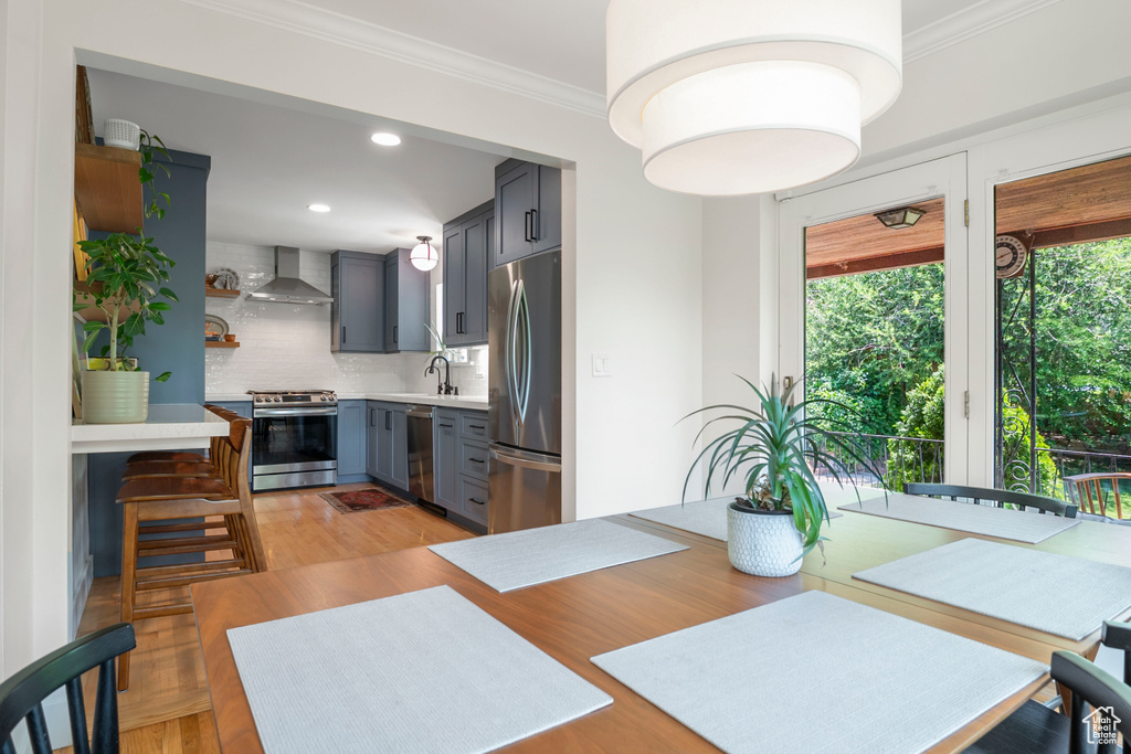 Kitchen featuring stainless steel appliances, wall chimney range hood, gray cabinets, decorative backsplash, and light countertops