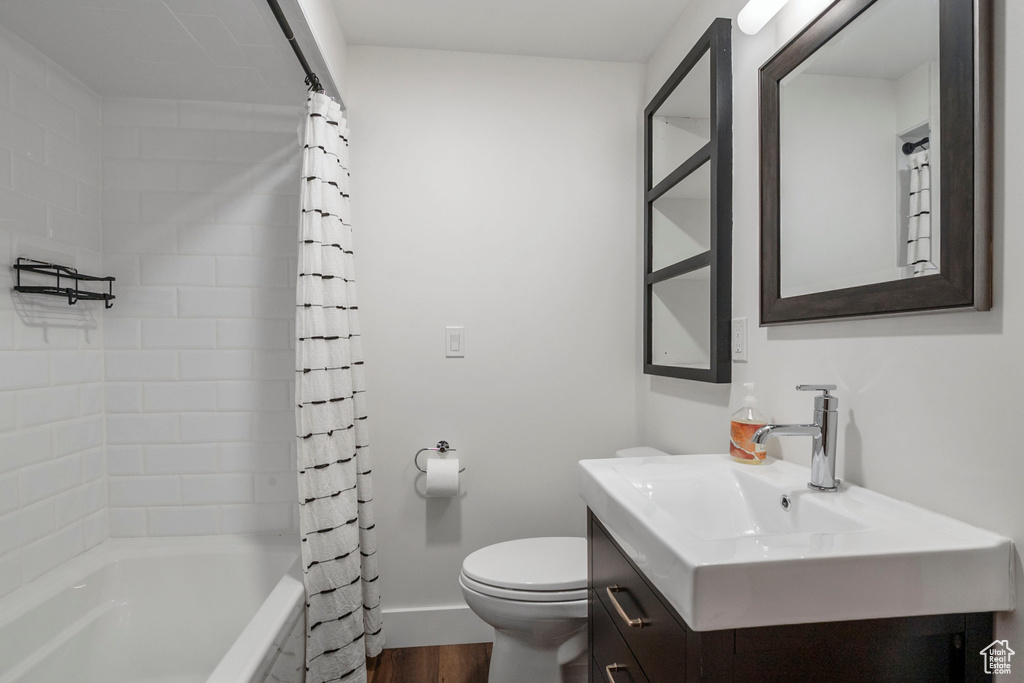 Bathroom featuring vanity, wood finished floors, and shower / bath combo with shower curtain