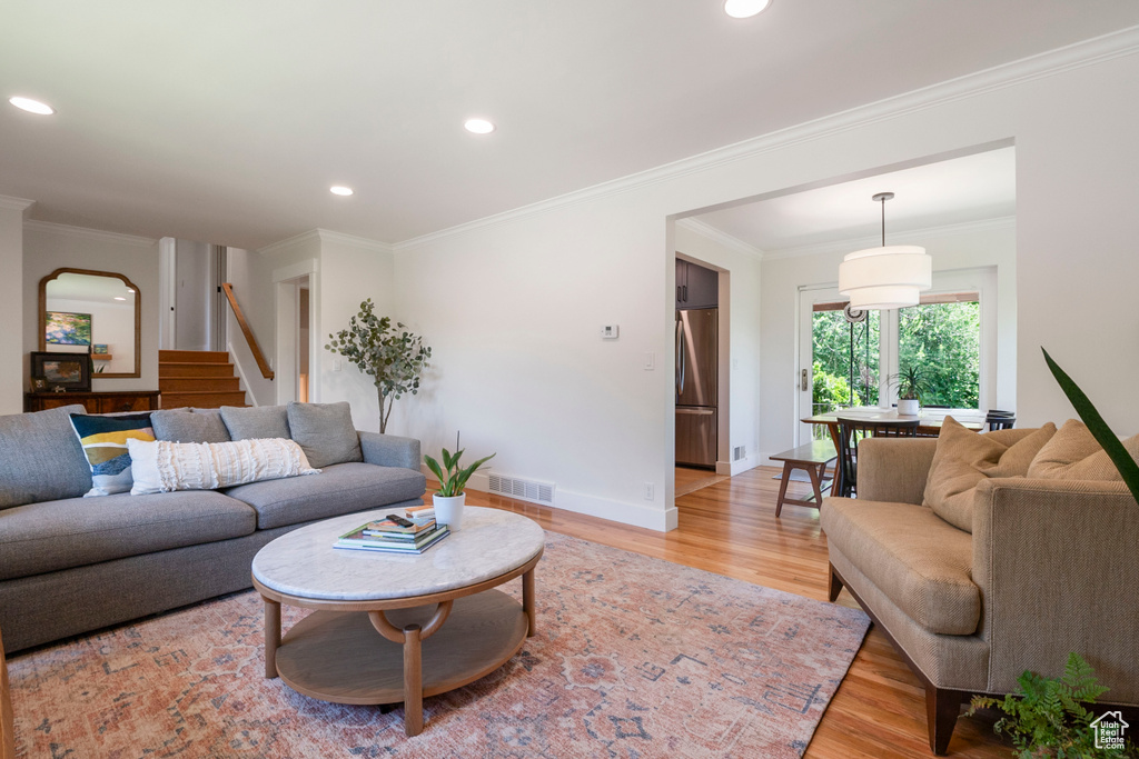Living area with light wood-style floors, stairway, recessed lighting, ornamental molding, and arched walkways