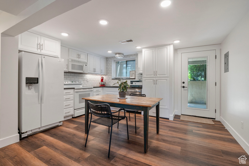 Kitchen with white appliances, healthy amount of natural light, white cabinets, decorative backsplash, and recessed lighting