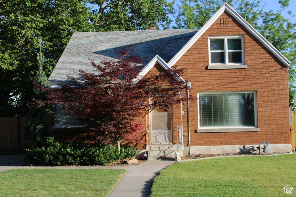 View of front of house featuring brick siding and a shingled roof