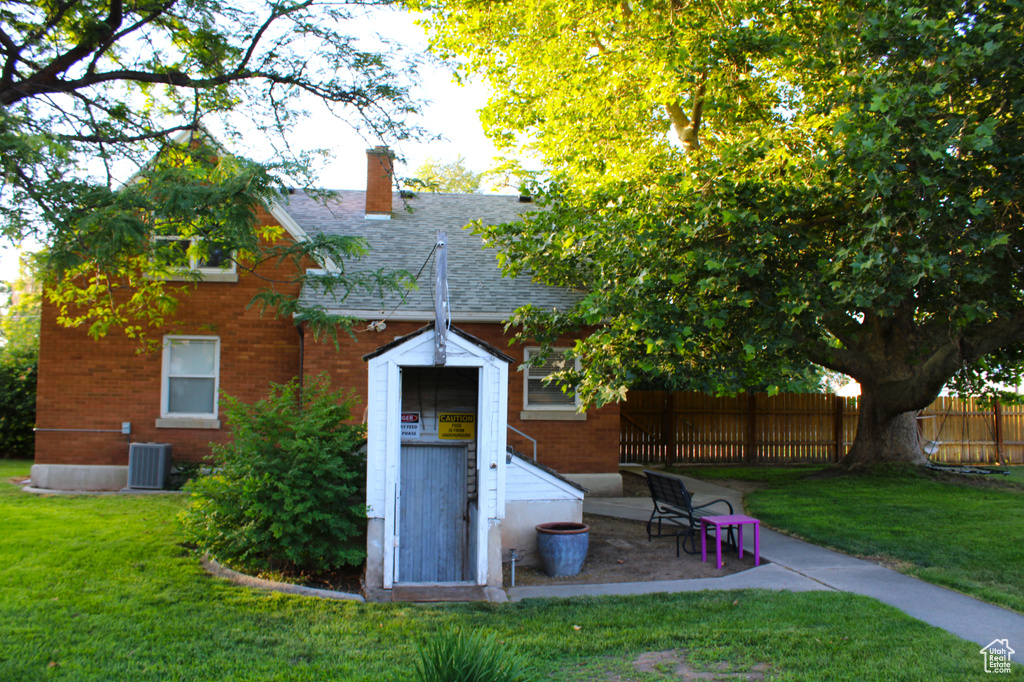 Back of house featuring brick siding, a chimney, and roof with shingles