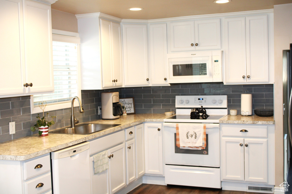 Kitchen with white appliances, light countertops, white cabinets, and recessed lighting