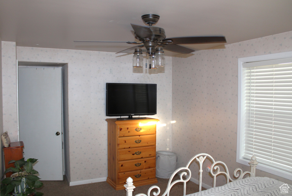 Bedroom with carpet floors, wallpapered walls, and ceiling fan