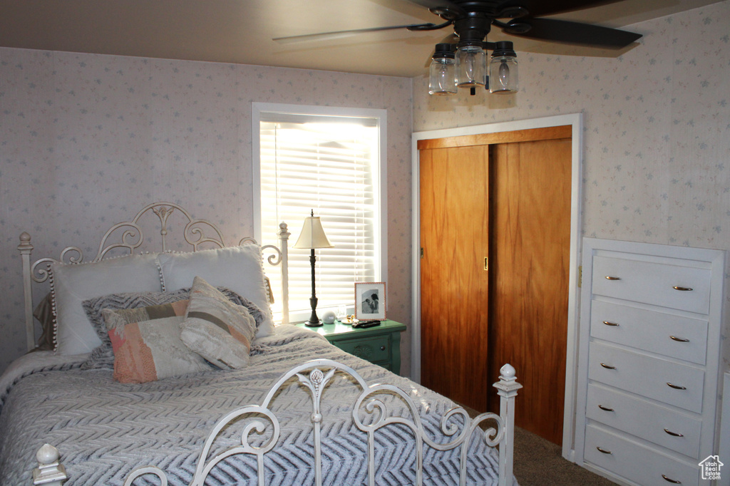 Carpeted bedroom featuring wallpapered walls, ceiling fan, and a closet