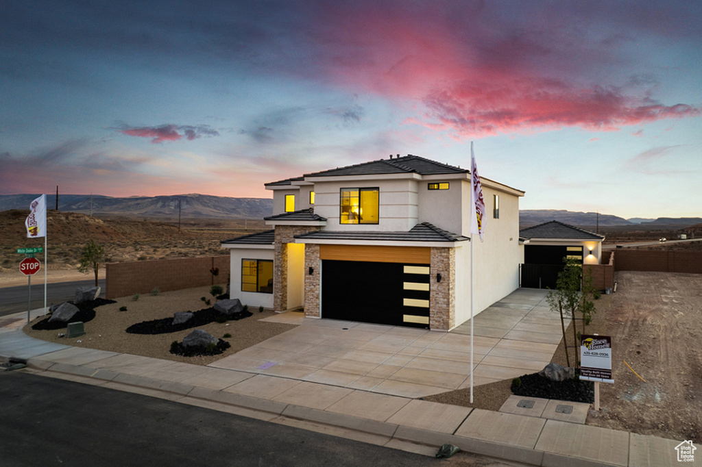 View of front of home featuring an attached garage, driveway, a mountain view, and stucco siding