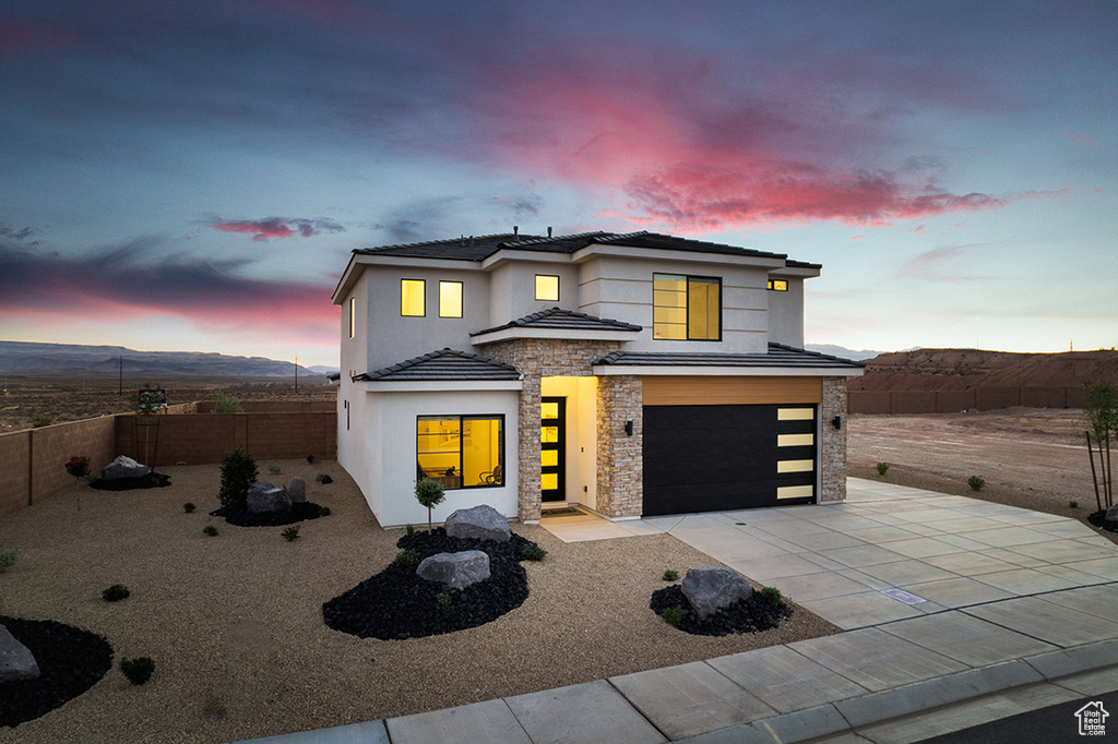 View of front of home with stone siding, a garage, stucco siding, concrete driveway, and a tiled roof