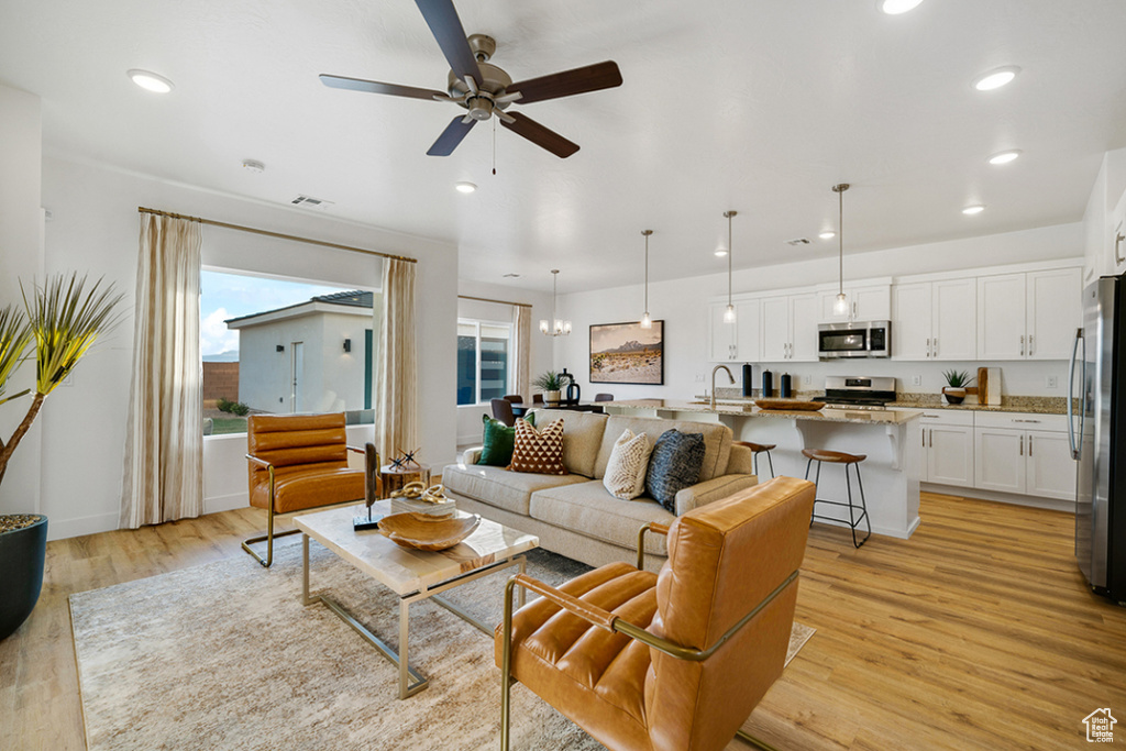 Living area with ceiling fan, light wood-style floors, and recessed lighting