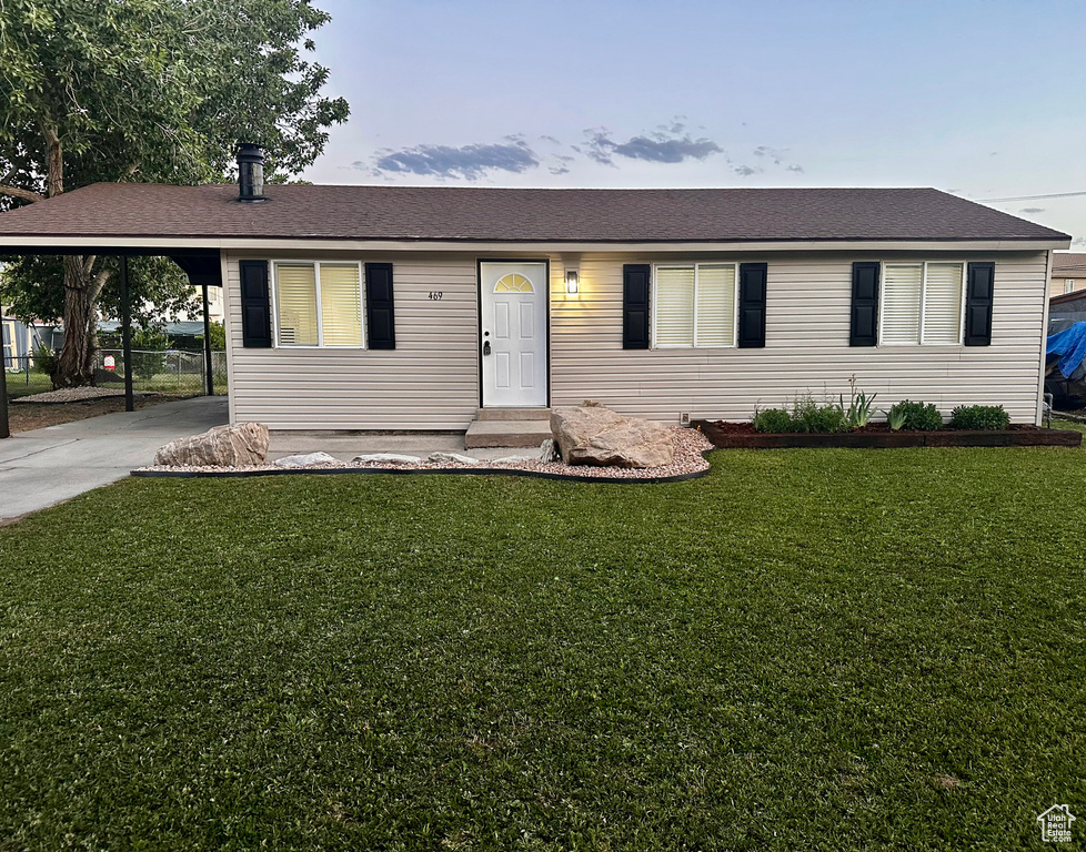 View of front of home featuring a front yard, a carport, and driveway