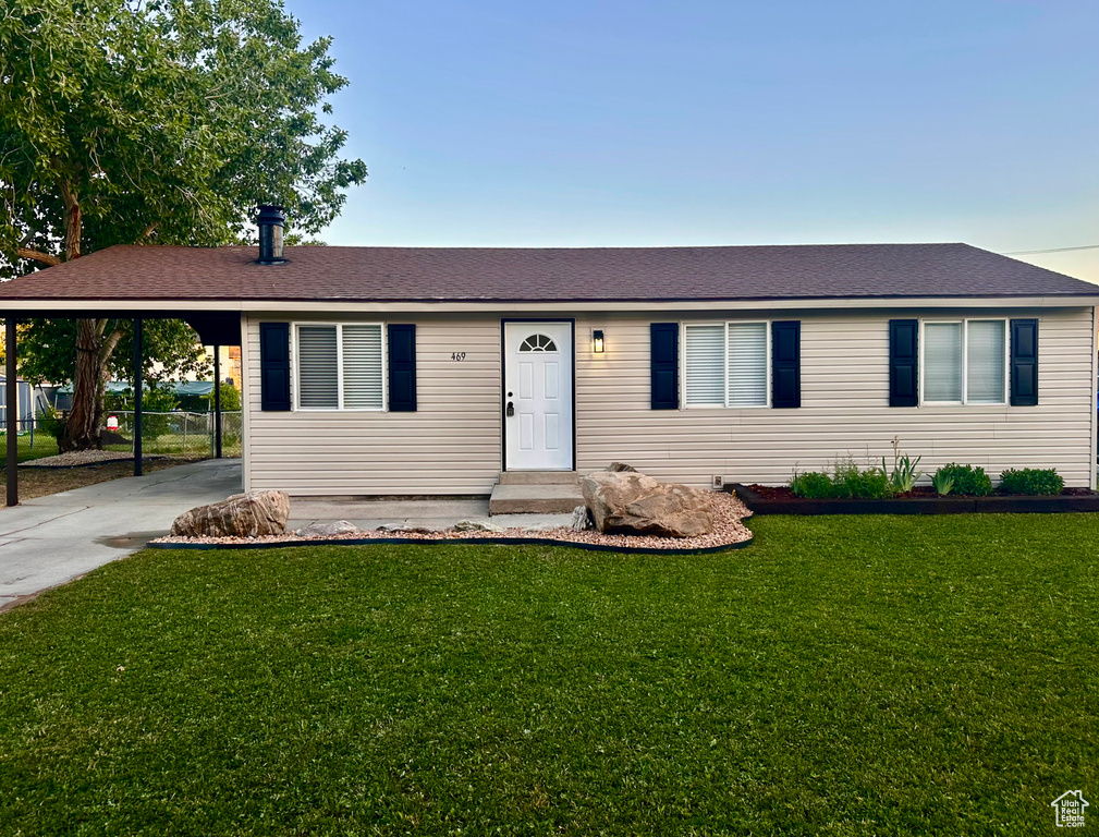 Ranch-style house featuring an attached carport, driveway, and roof with shingles