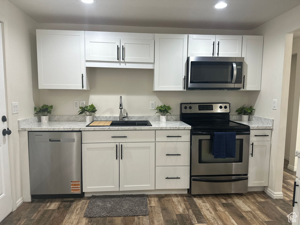 Kitchen with stainless steel appliances, recessed lighting, dark wood-type flooring, and white cabinetry