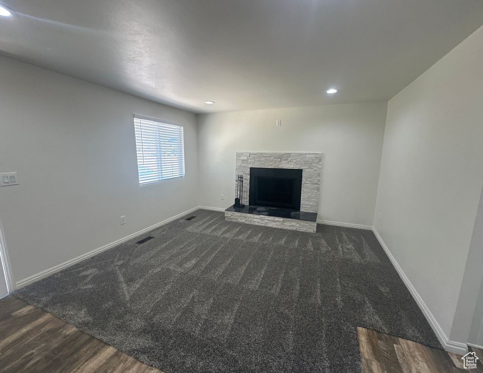 Unfurnished living room featuring a stone fireplace, recessed lighting, wood finished floors, and carpet floors