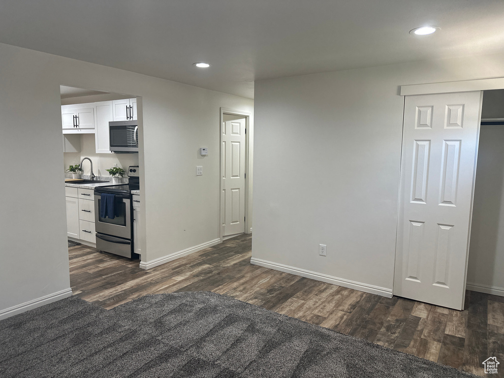 Kitchen with appliances with stainless steel finishes, dark wood-type flooring, recessed lighting, and white cabinets