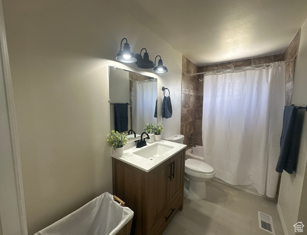 Bathroom featuring vanity, shower / bathtub combination with curtain, and tile patterned flooring