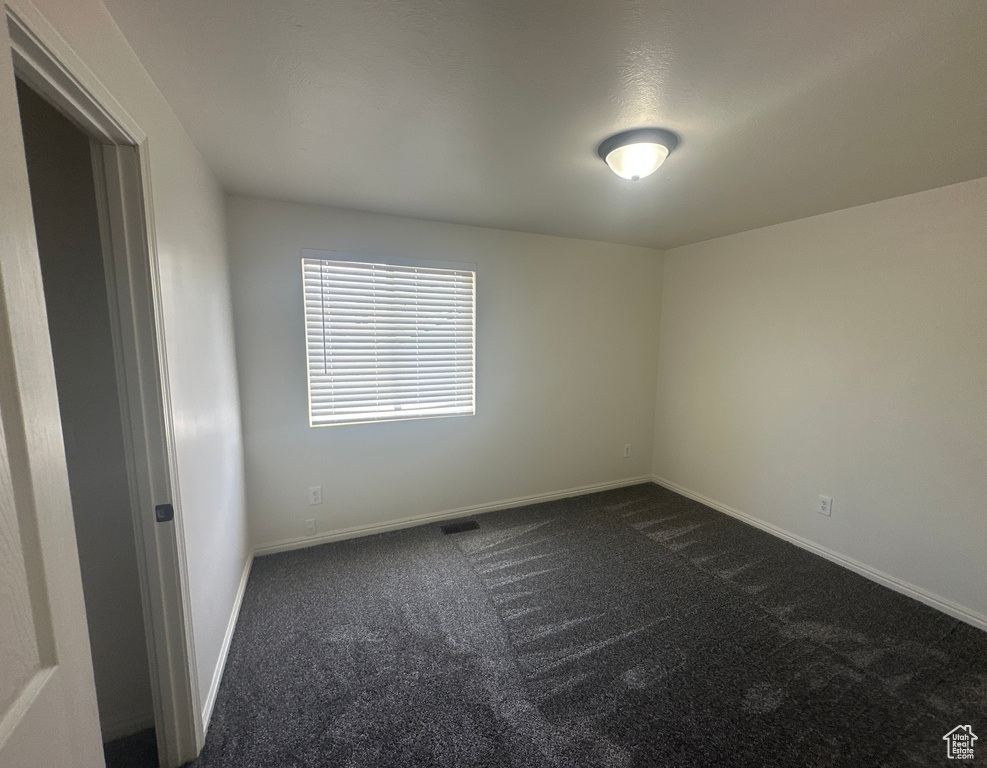 Unfurnished room featuring dark carpet