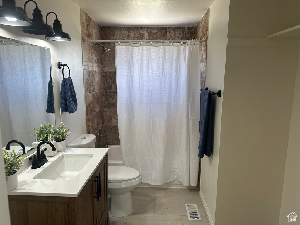Bathroom featuring vanity, shower / tub combo with curtain, and tile patterned floors