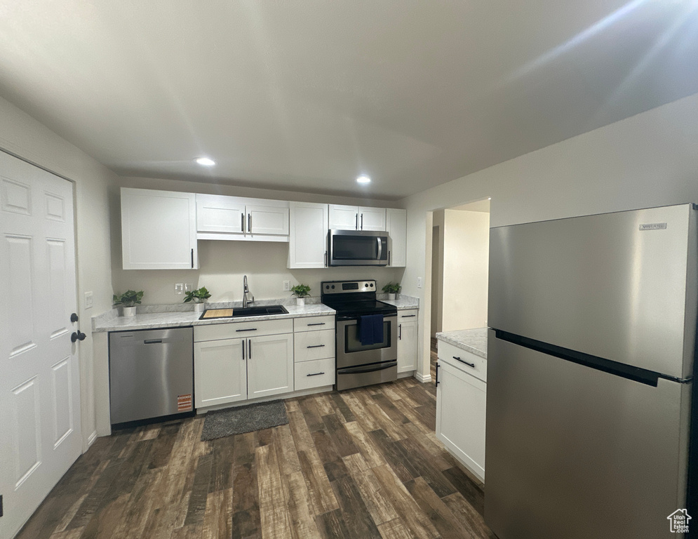 Kitchen featuring stainless steel appliances, recessed lighting, dark wood finished floors, white cabinets, and light stone counters