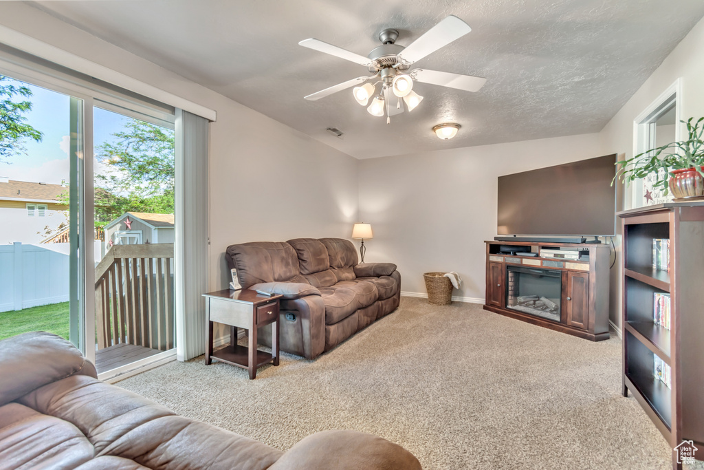 Carpeted living area featuring ceiling fan and baseboards