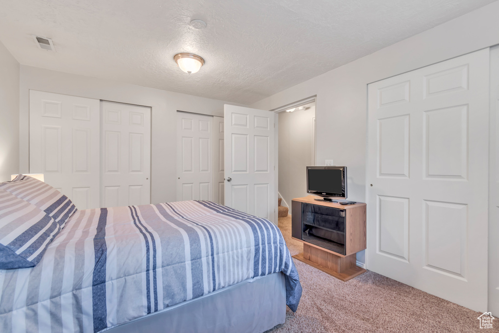 Carpeted bedroom with two closets and a textured ceiling