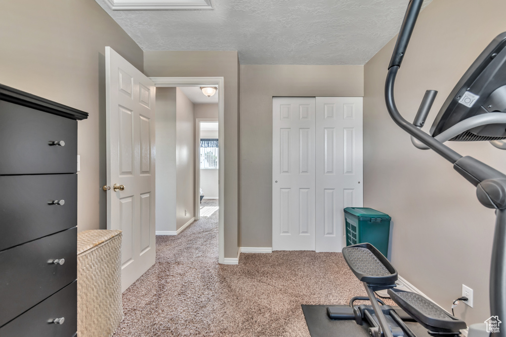 Exercise area with carpet flooring and a textured ceiling