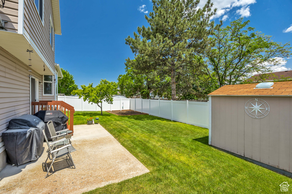 Fenced backyard featuring a patio area and a shed