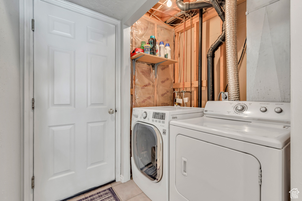 Laundry area featuring washing machine and dryer and light tile patterned floors