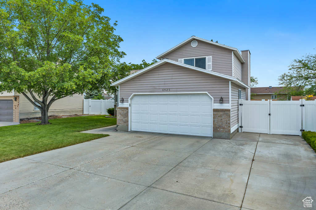 View of home's exterior featuring a gate, driveway, a garage, a chimney, and brick siding