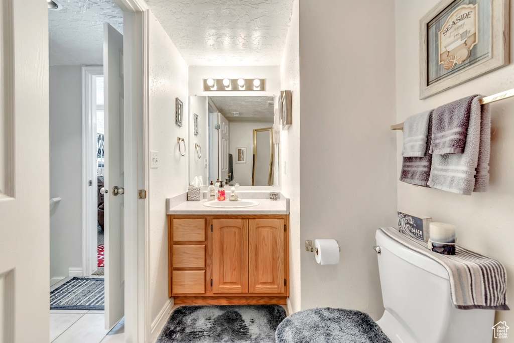 Half bath featuring vanity, a textured ceiling, and tile patterned flooring