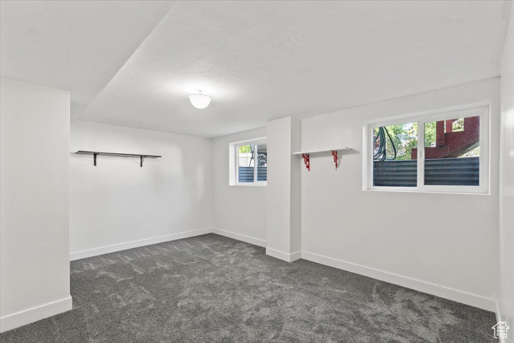 Empty room featuring dark carpet and baseboards