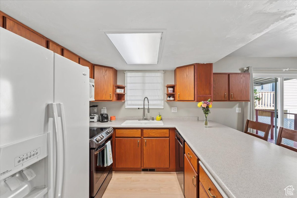 Kitchen featuring white appliances, open shelves, light countertops, and brown cabinets