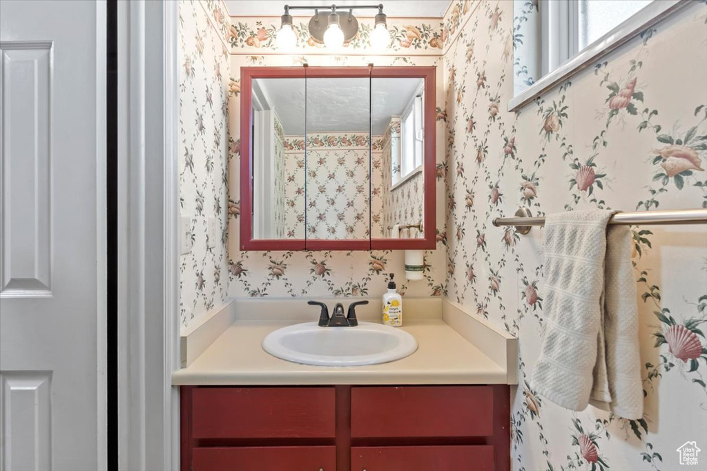 Bathroom featuring wallpapered walls and vanity