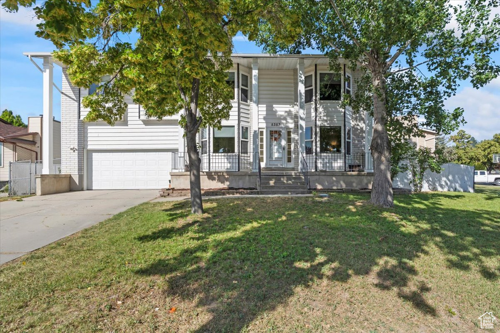 View of front of home with covered porch, driveway, an attached garage, and a front lawn
