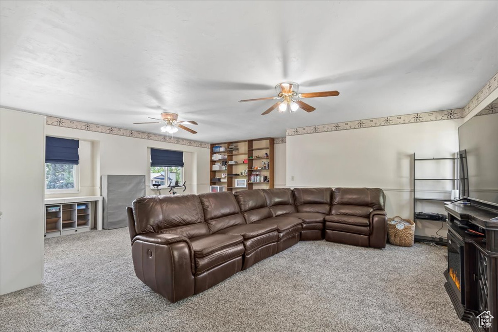 Carpeted living room featuring ceiling fan and built in features