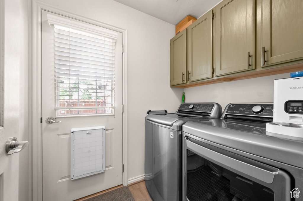Laundry area with independent washer and dryer, cabinet space, and light wood-type flooring