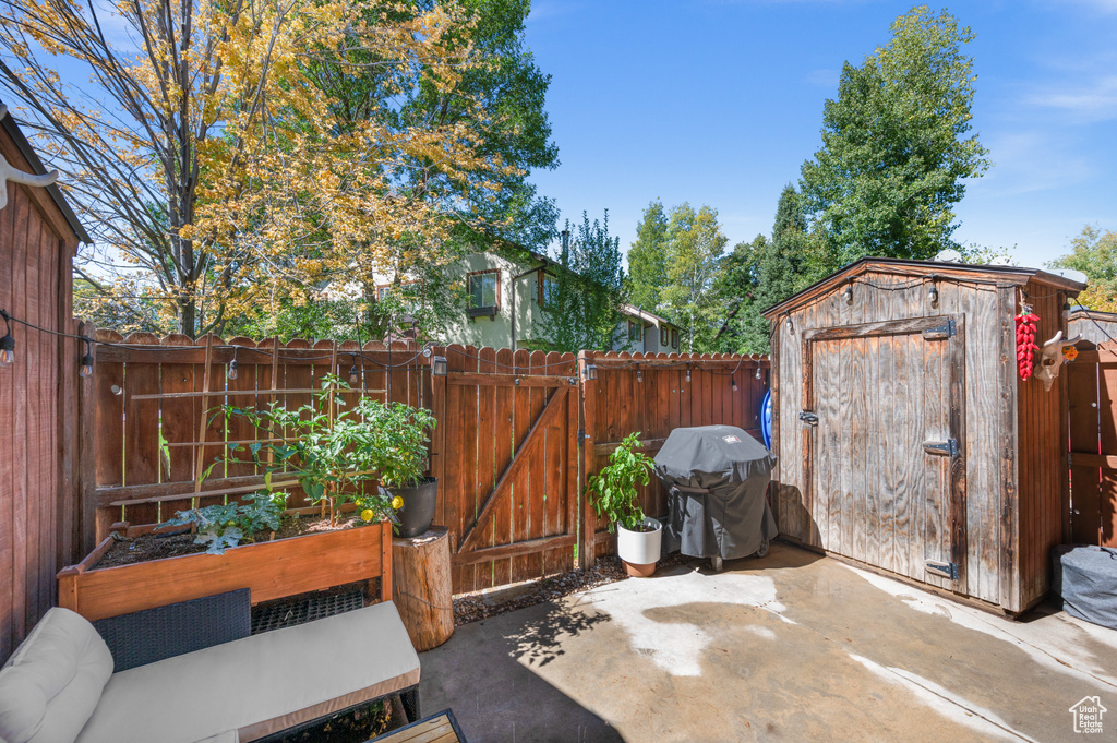Fenced backyard featuring area for grilling, a storage unit, a gate, a patio, and a garden
