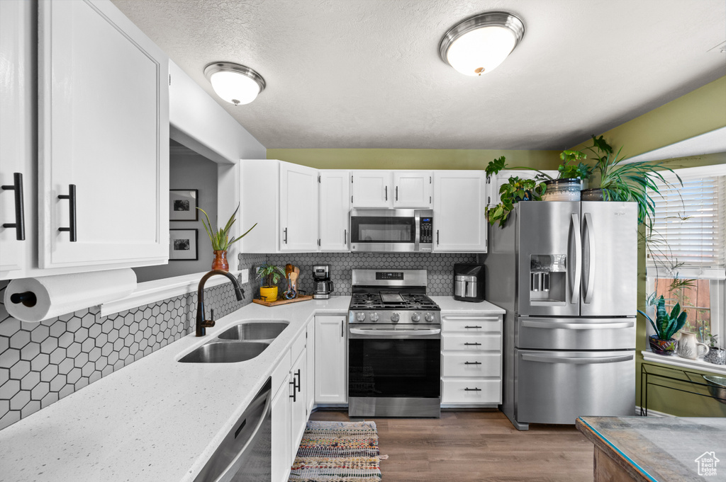 Kitchen featuring stainless steel appliances, white cabinetry, backsplash, and dark wood finished floors