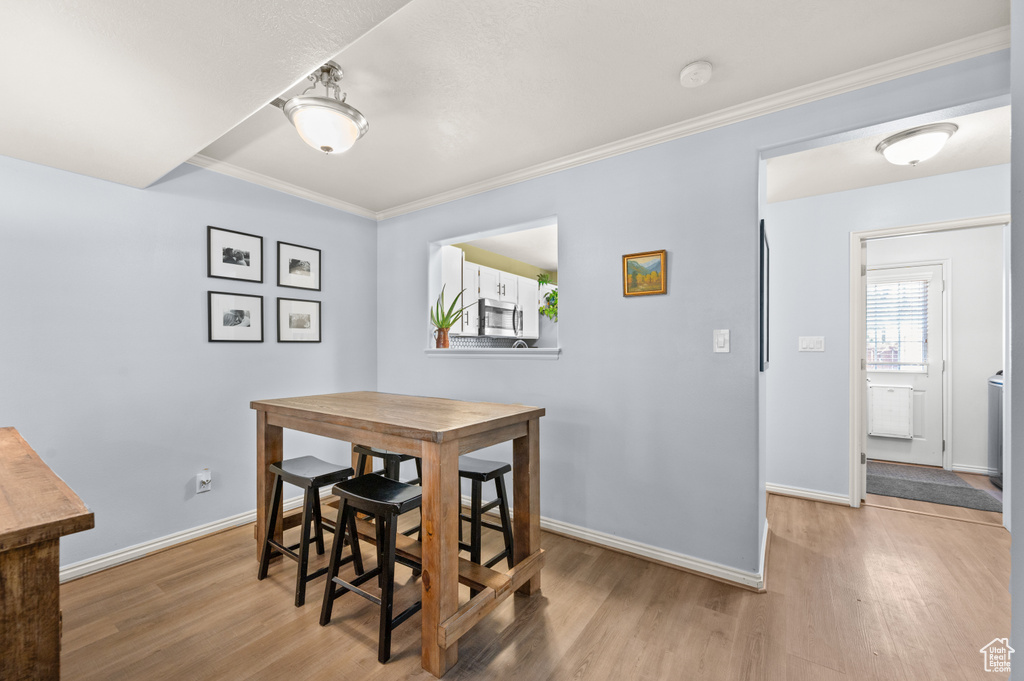 Dining space featuring light wood-style flooring and crown molding