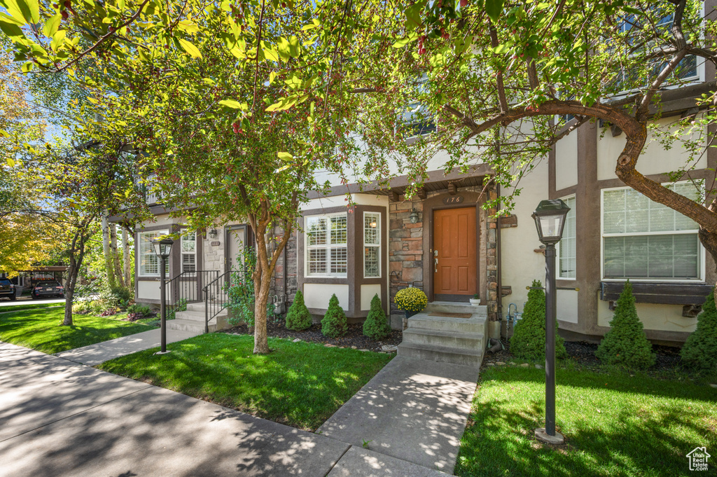 View of front of home featuring a front yard, stone siding, and stucco siding